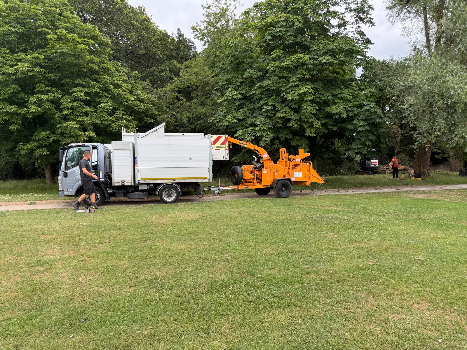 Isuzu tree surgery truck towing a Bandit woodchipper on-site