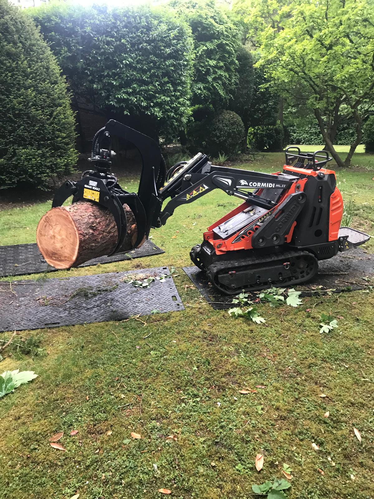 Cormidi loader carrying a large log section during garden clearance